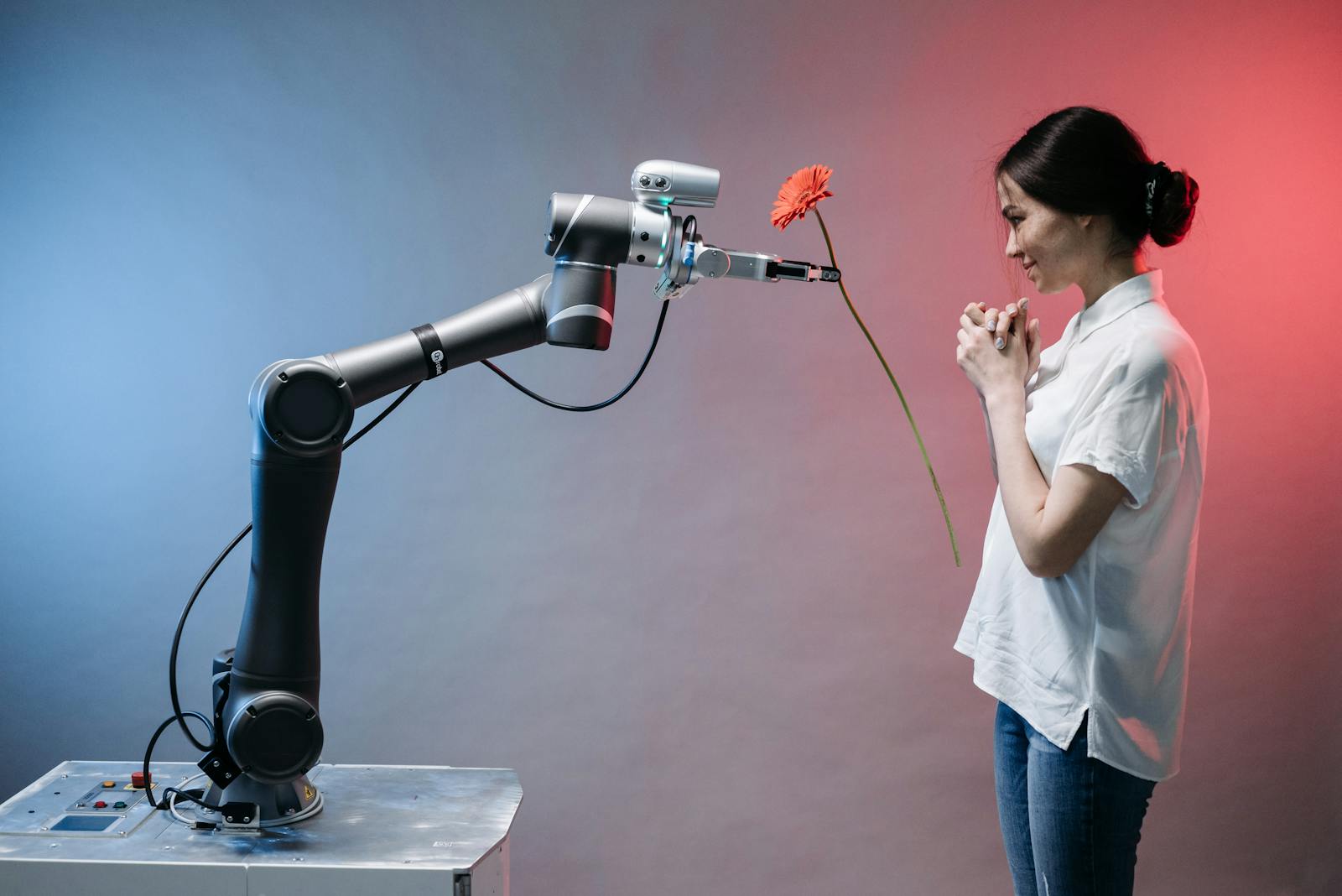 A robotic arm offers a flower to a woman in a display of technology and human connection.