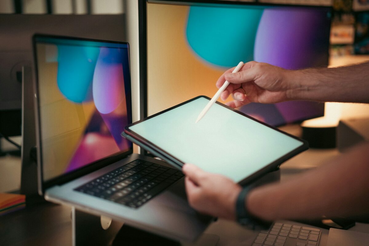 A person holding a pen and writing on a laptop
