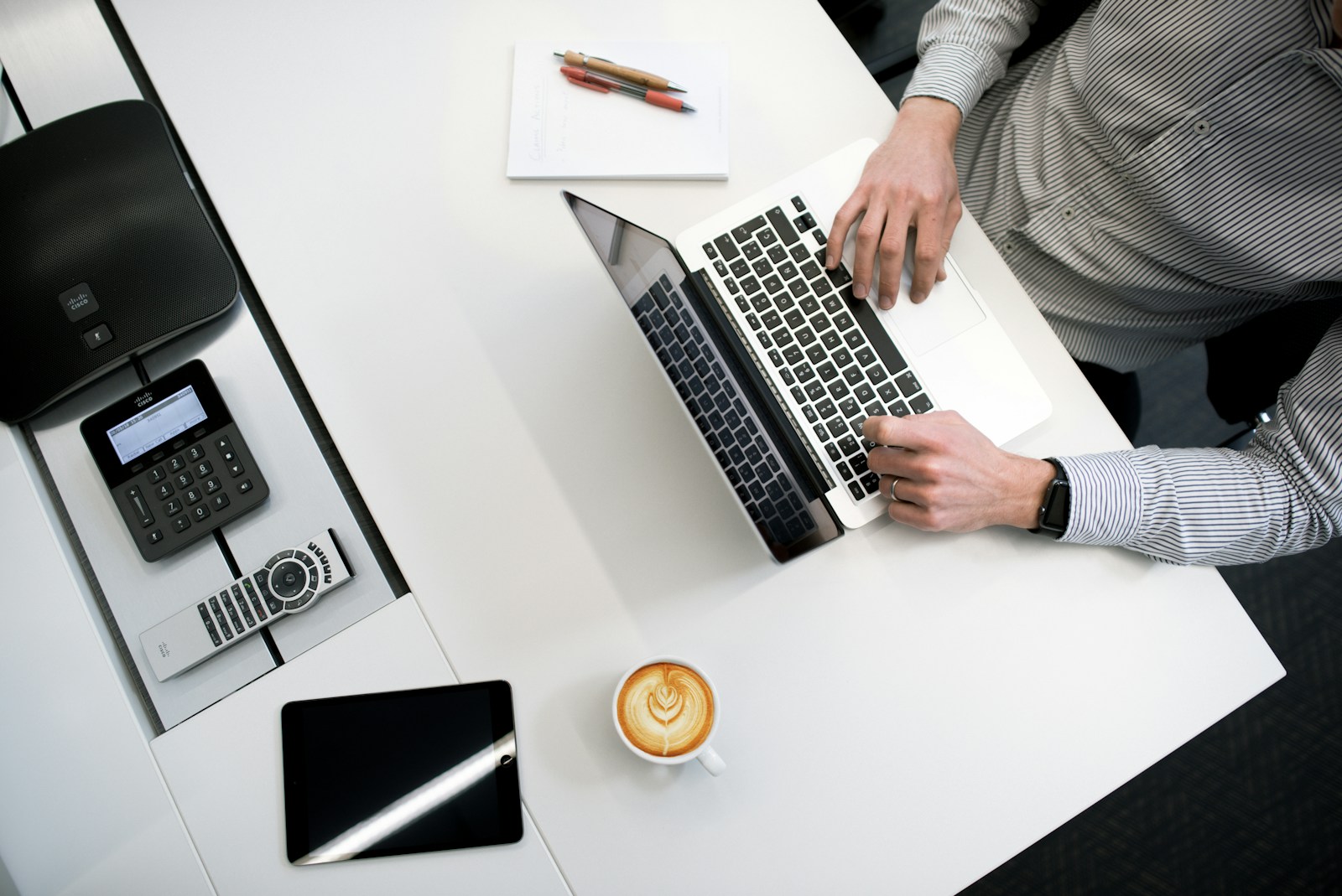 Top-down view of professionals working on a laptop at a modern desk, representing digital sales and quoting processes with SAP CPQ for Energy and Utilities.