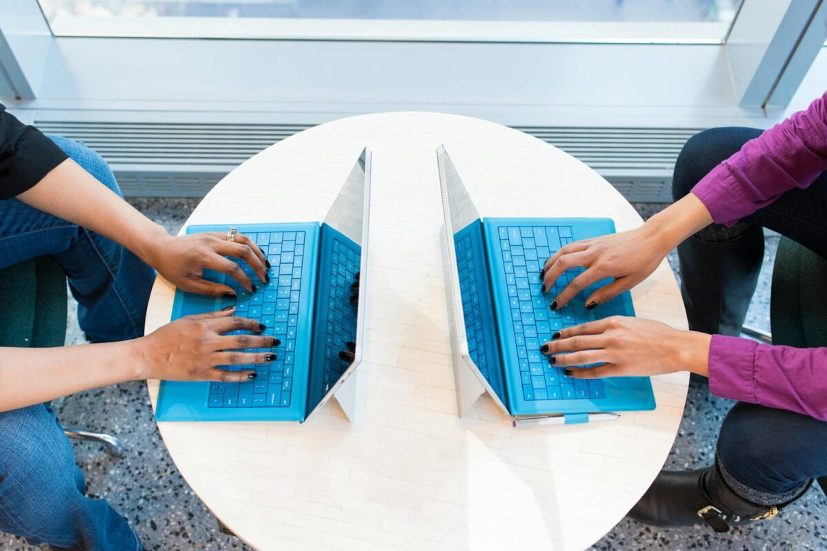 Two people working on blue laptops at a round table, focusing on teamwork and technology.