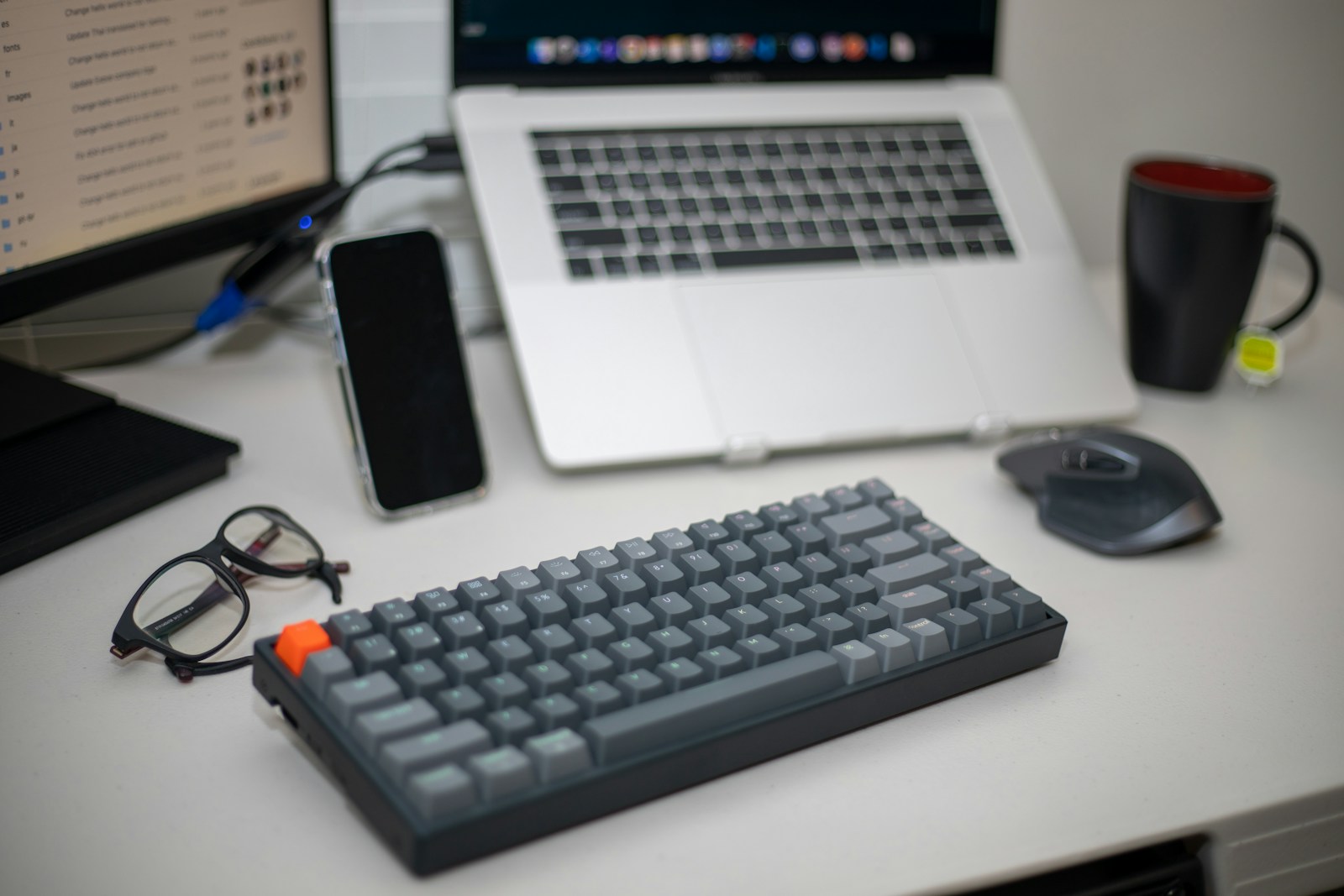 Workspace with laptop, keyboard, smartphone, and notebook on a desk, representing preparation and collaboration during a CPQ discovery workshop session.