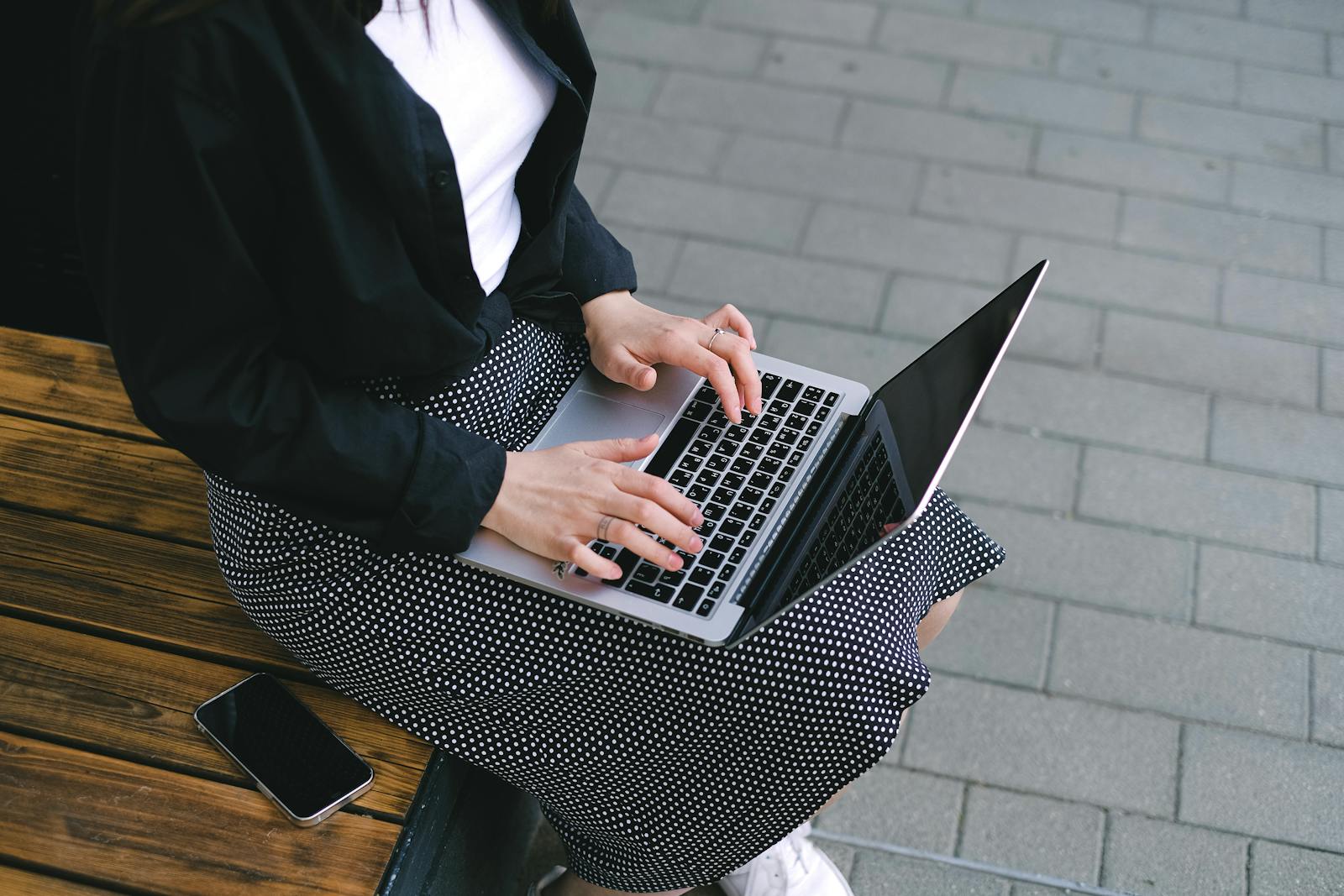Woman sitting outdoors typing on a laptop, embodying freelance and digital nomad lifestyle.