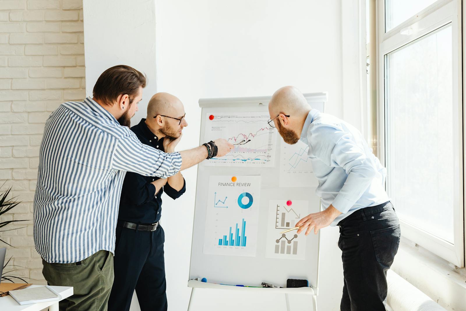 Team analyzing charts on a flipchart during a meeting, discussing data and optimizing sales processes in a collaborative office environment.