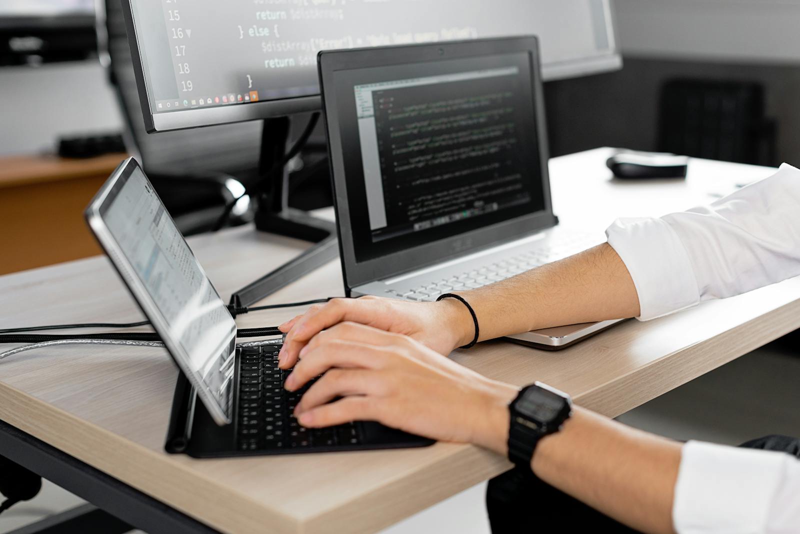 Candid shot of a programmer at work using multiple screens to code in a modern office.