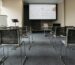 An empty conference room with chairs, a projector screen, and presentation setup.