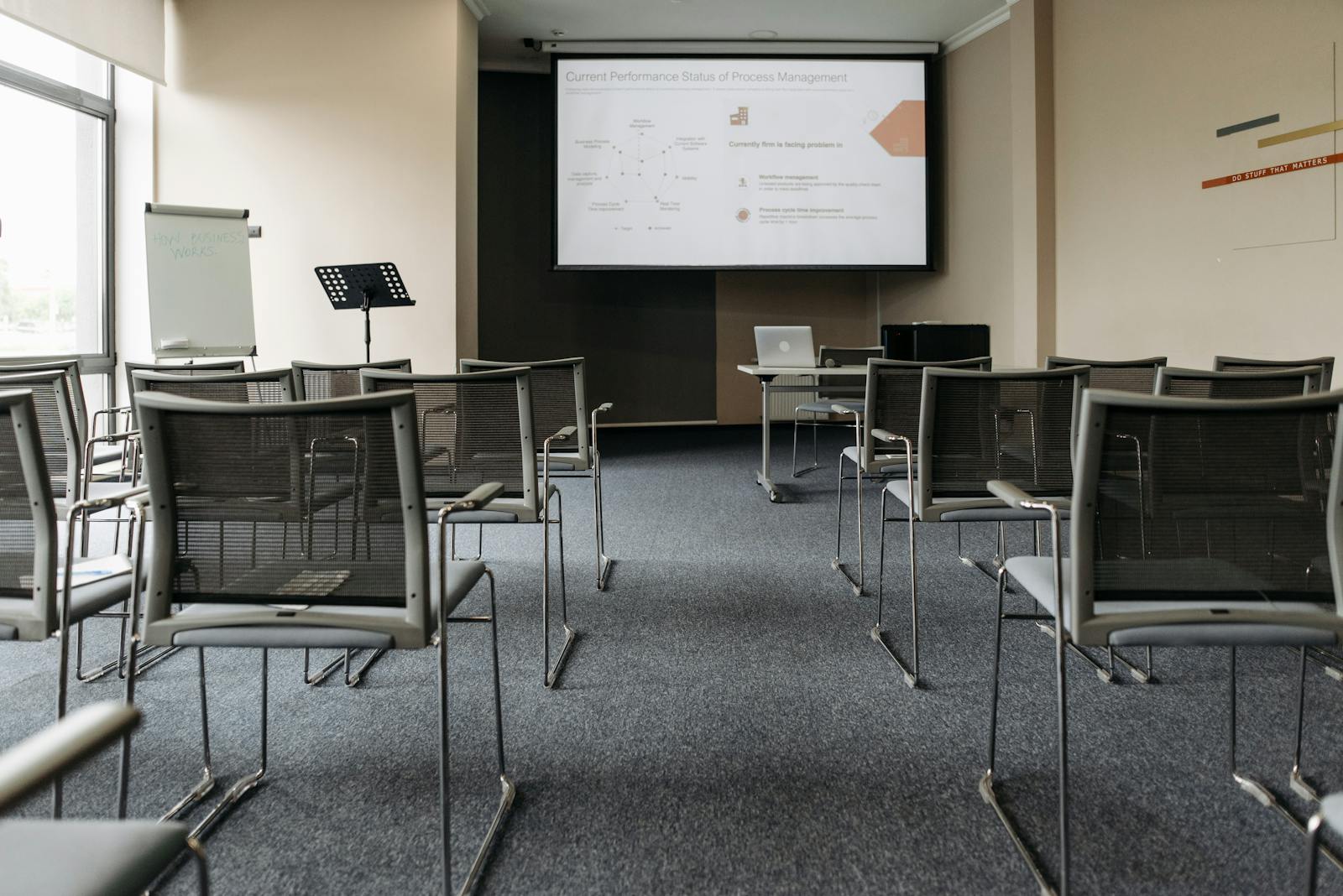 An empty conference room with chairs, a projector screen, and presentation setup.
