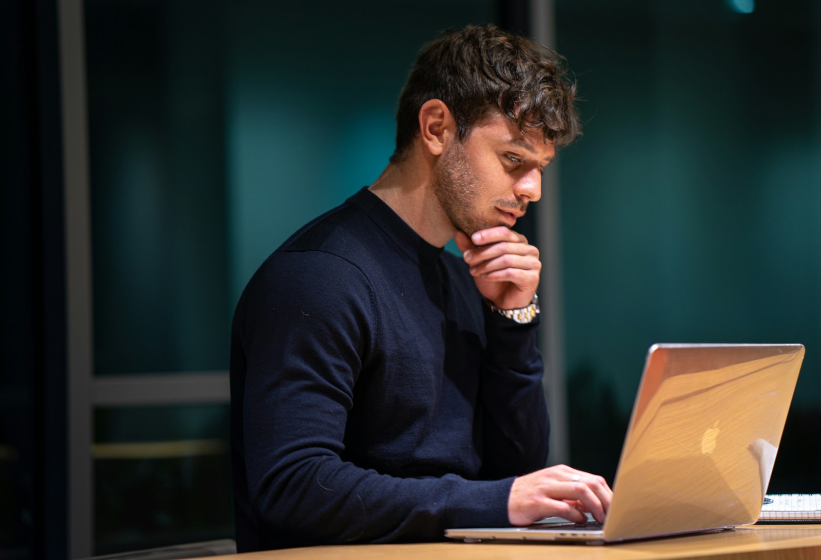 Professional working on a laptop, thoughtfully analyzing data, illustrating CPQ processes and decision-making in a focused workspace.