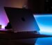 A MacBook reflecting vibrant neon lights in a dimly lit room setting.