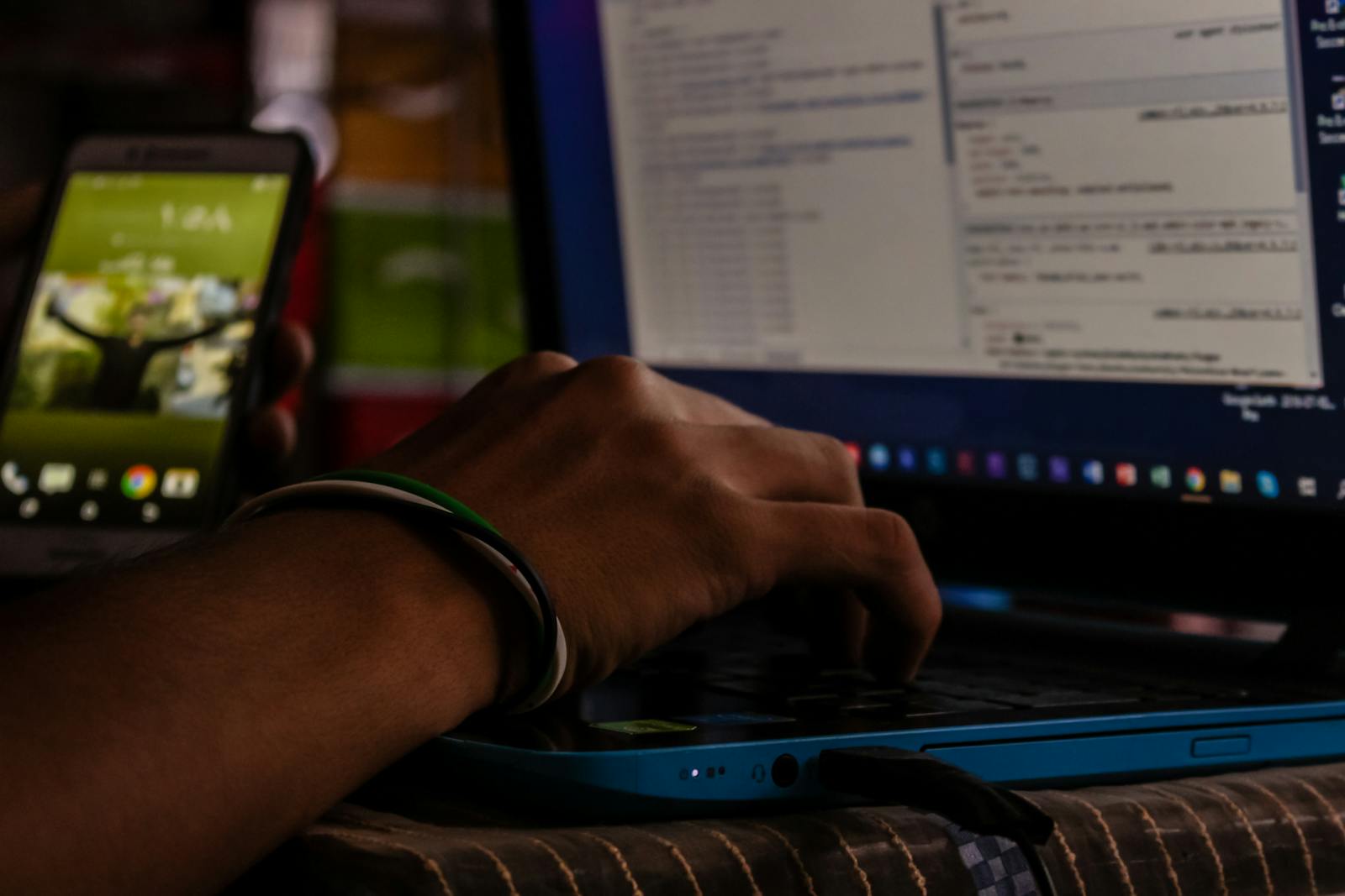 Developer working on a laptop with mobile and coding interface in the background, representing a hands-on SAP CPQ Sandbox Training Program for testing and skill development.