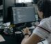 Man focused on coding at his workstation in a modern office.