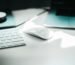 Apple Magic mouse beside keyboard on white surface