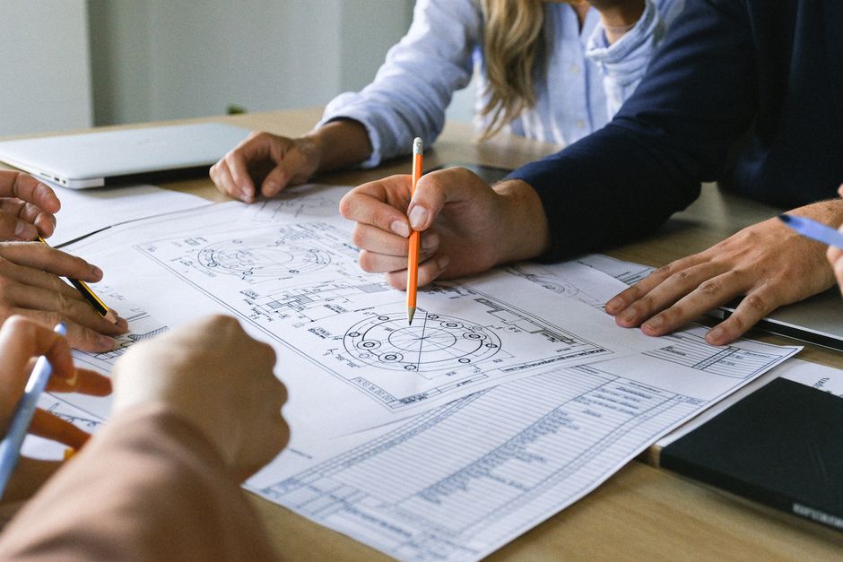 Engineering team reviewing technical blueprints to align product configuration with quoting requirements