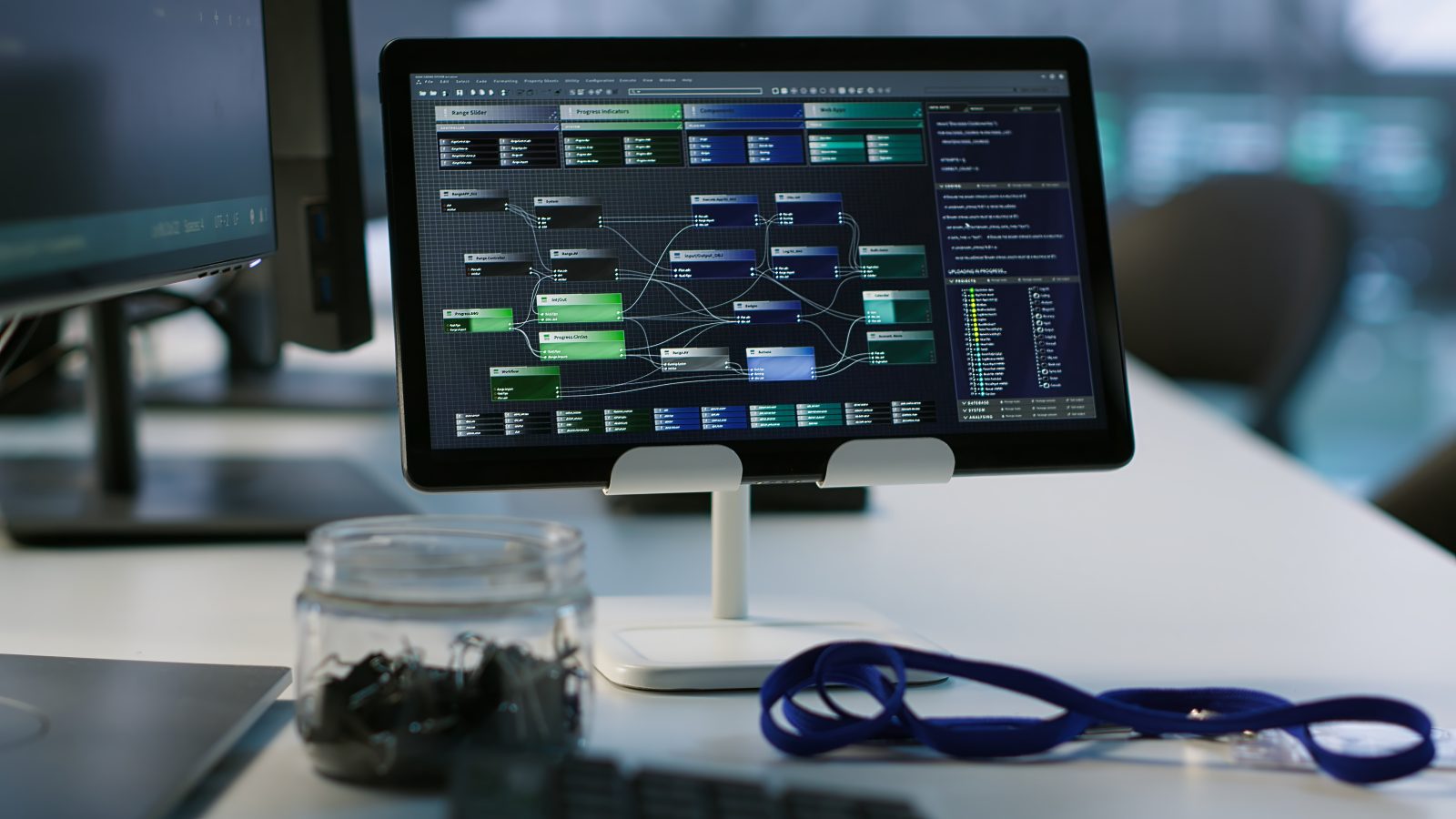 A desktop monitor in an operations room showing a node based data flow diagram