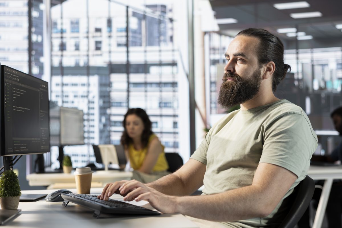 Developer reading source code on screen in an open plan office