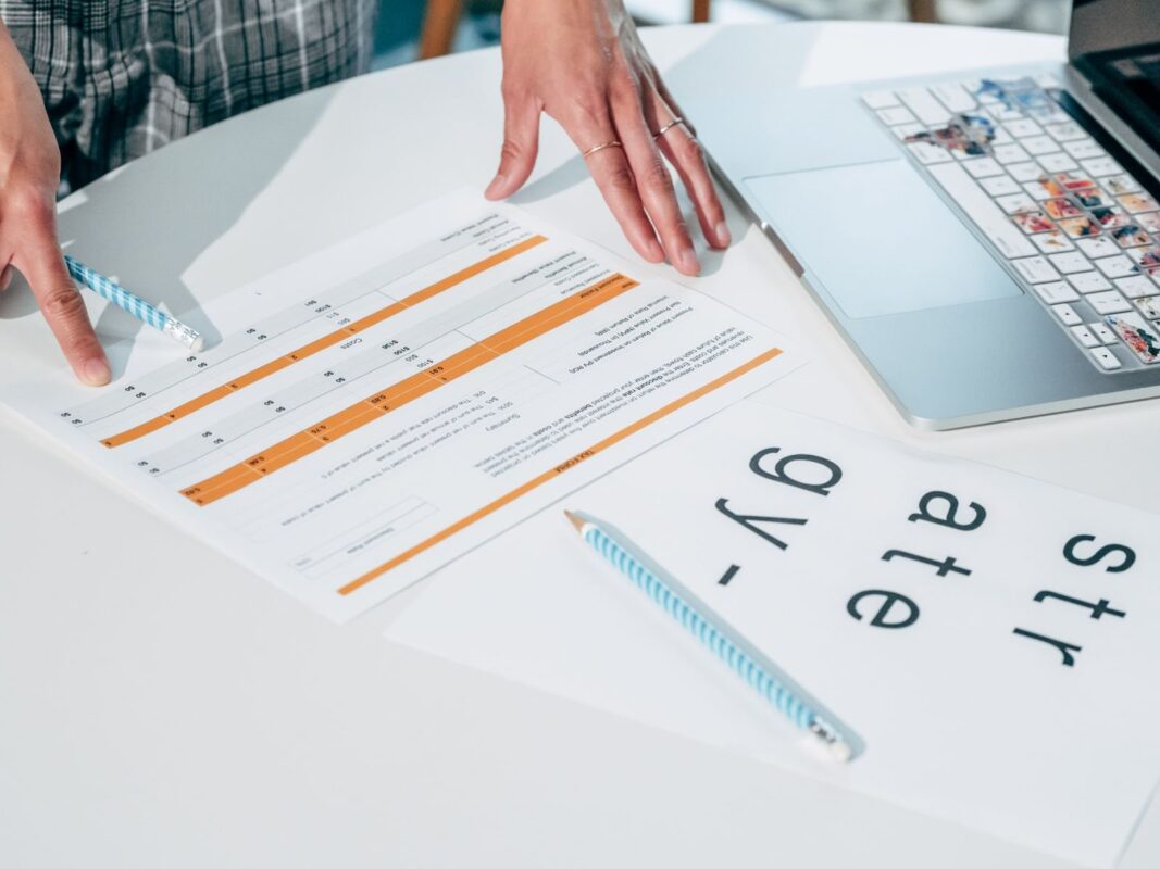 Two people reviewing a printed business document with an orange line item table on an office desk