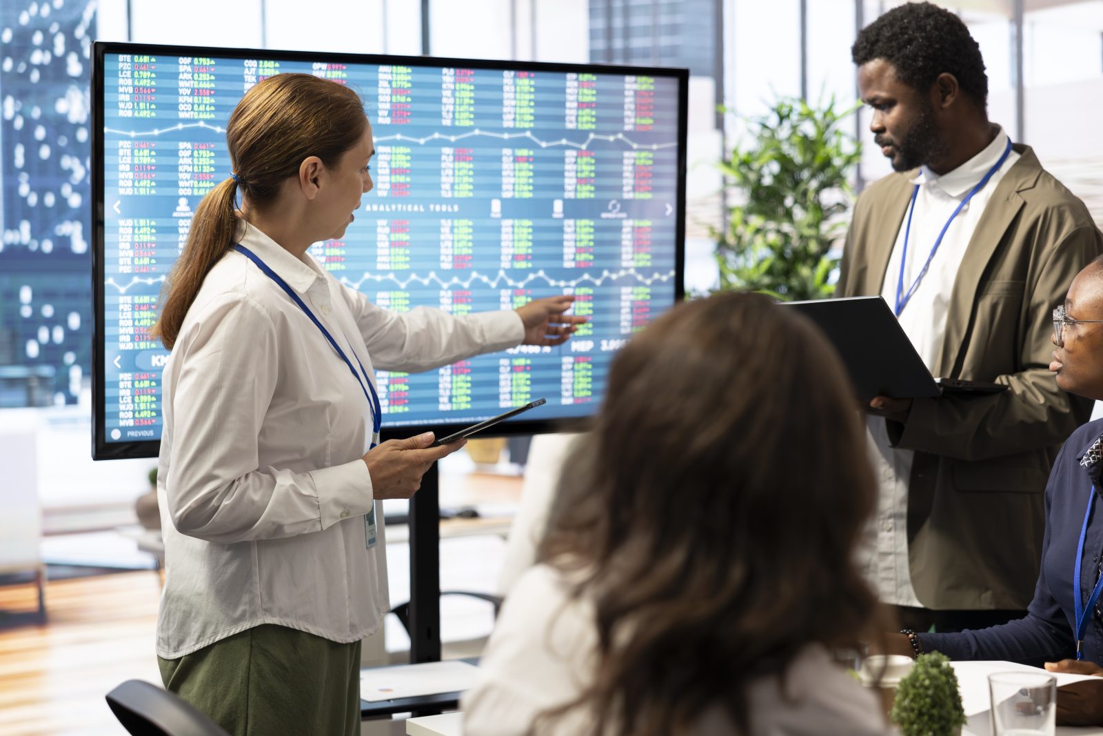 A project team reviewing data on a large wall display during a briefing in an open plan office
