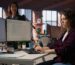 Software developer reviewing code on two monitors in an office
